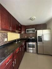 9351 Lime Bay Boulevard, Unit 102 Tamarac, FL 33321 - Photo 14 of 14 a kitchen with stainless steel appliances granite countertop a stove a sink and a microwave