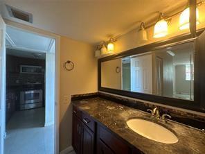 9351 Lime Bay Boulevard, Unit 102 Tamarac, FL 33321 - Photo 6 of 14 a bathroom with a granite countertop sink and a mirror