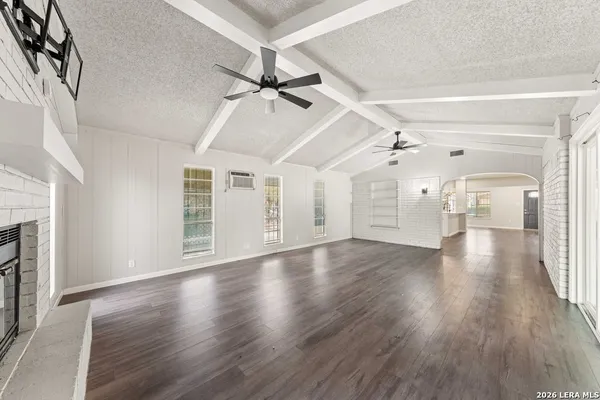 a view of an empty room with wooden floor fireplace and a window
