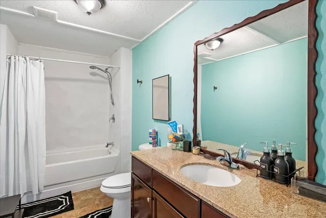 a bathroom with a granite countertop sink toilet and shower