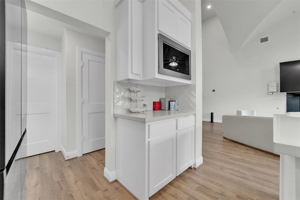 3520 Helios Lane Corinth, TX 76208 - Photo 12 of 37 Built-in wet bar featuring white shaker-style cabinetry, a stainless steel microwave, light-toned countertop, and a decorative tile backsplash