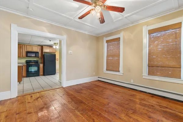 a view of an empty room with window and wooden floor