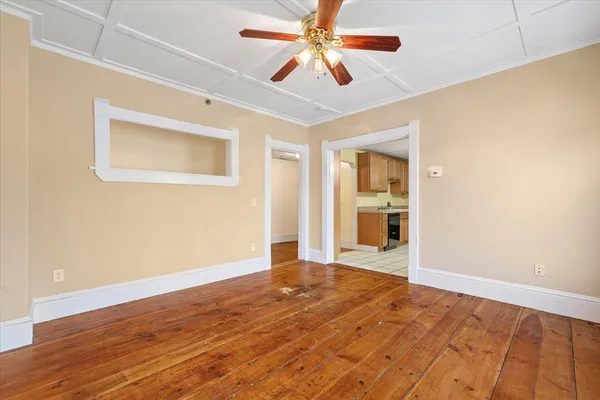 a view of a big room with wooden floor a ceiling fan and windows