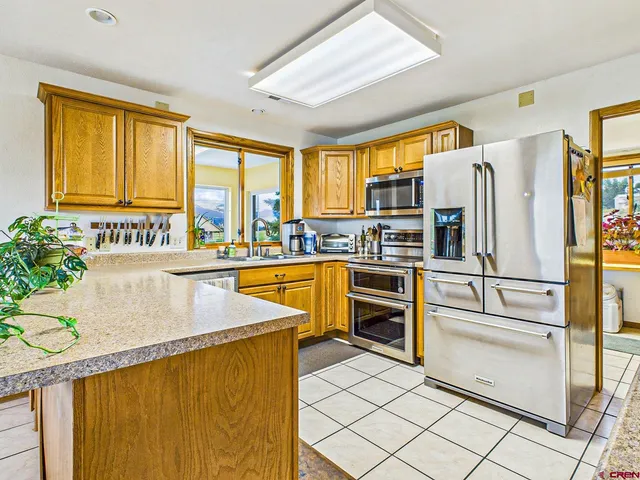 a kitchen with stainless steel appliances granite countertop a refrigerator a stove and a sink with cabinets