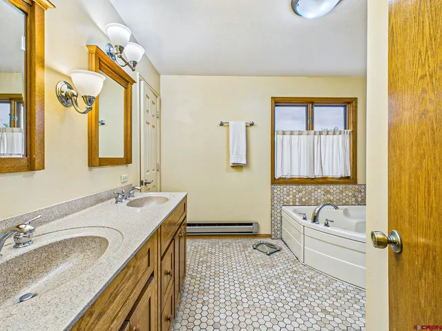 a bathroom with a granite countertop sink a mirror a bathtub and next to a window