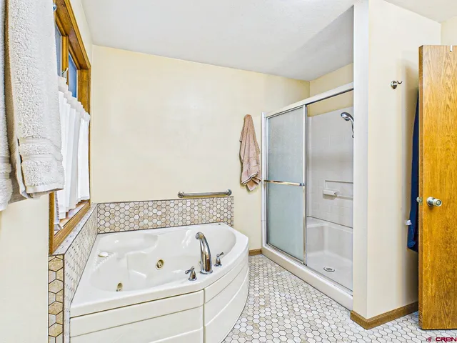 a bathroom with a tub a mirror and a shower