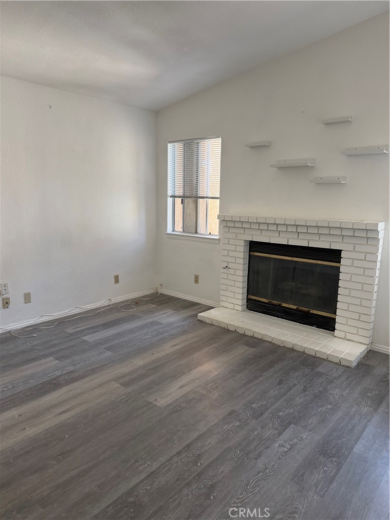 18602 Cocqui Road Apple Valley, CA 92307 - Photo 7 of 16 an empty room with wooden floor and fireplace