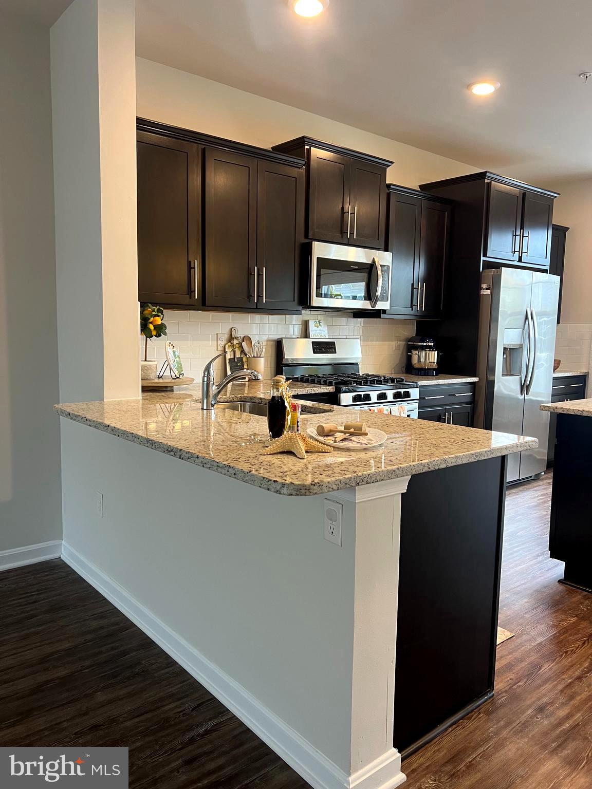 3106 Laurel Hill Road Hanover, MD 21076 - Photo 5 of 25 a kitchen with stainless steel appliances granite countertop a stove a refrigerator a sink a microwave and wooden floor