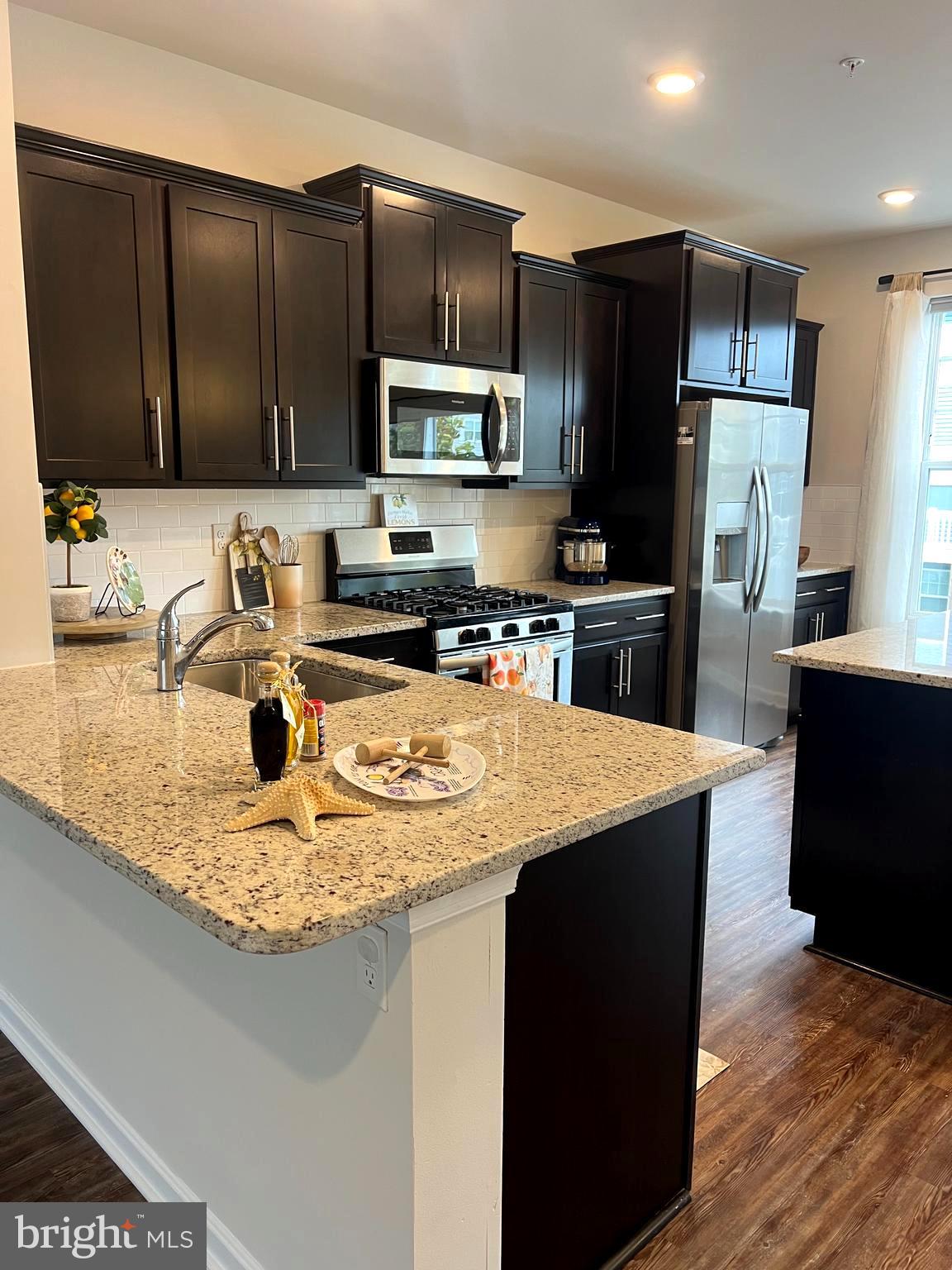 3106 Laurel Hill Road Hanover, MD 21076 - Photo 7 of 25 a kitchen with kitchen island granite countertop stainless steel appliances a sink a stove a microwave a sink a refrigerator and cabinets