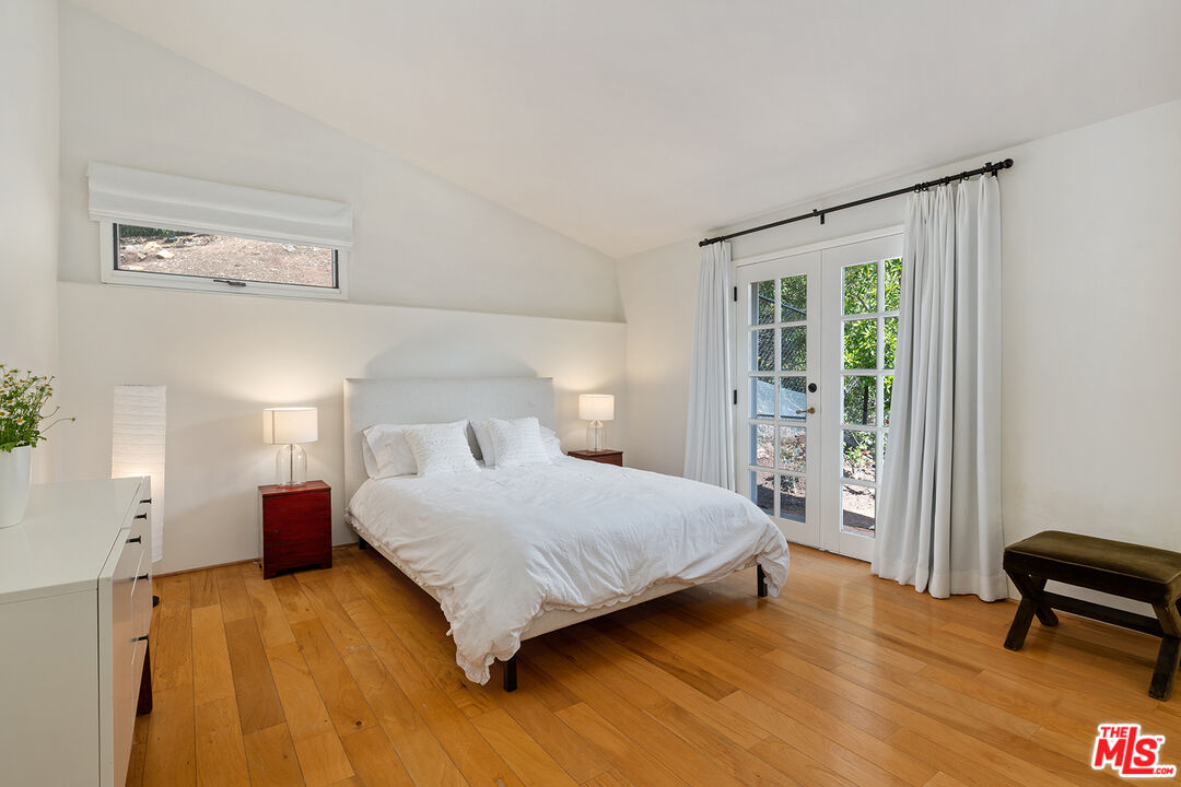 2382 Live Oak Meadows Road Malibu, CA 90265 - Photo 35 of 50 a bedroom with a bed a table and painting on the wall
