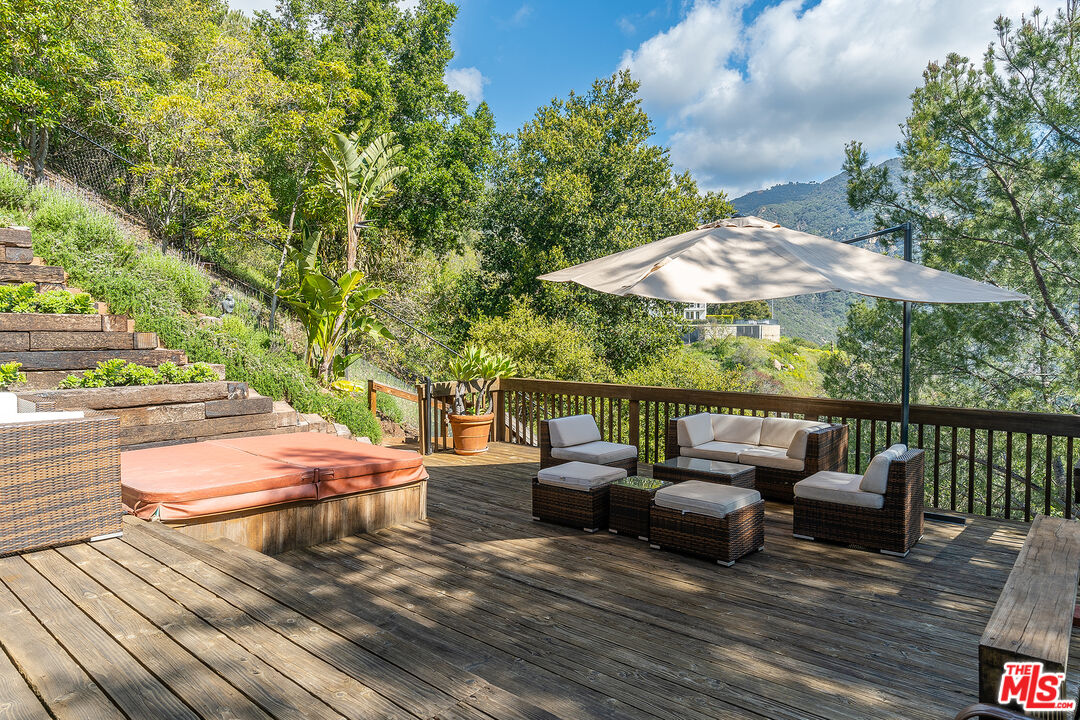 2382 Live Oak Meadows Road Malibu, CA 90265 - Photo 42 of 50 a view of a patio with couches table and chairs under an umbrella with wooden floor