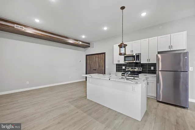 a kitchen with kitchen island a white counter top space stainless steel appliances and cabinets