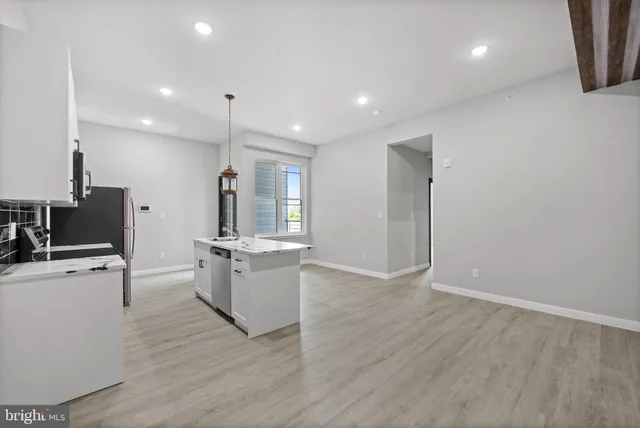 a large kitchen with stainless steel appliances a large counter top a stove and a refrigerator