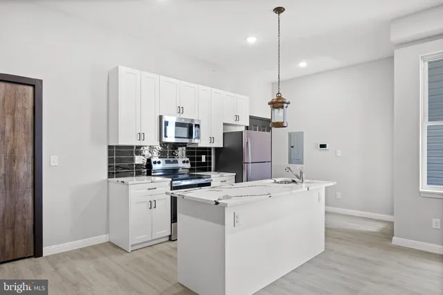 a kitchen that has a lot of cabinets a sink and a wooden floor