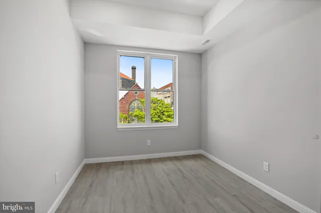 a view of an empty room with window and wooden floor