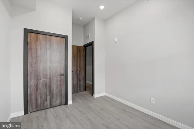 an empty room with wooden floor and closet area