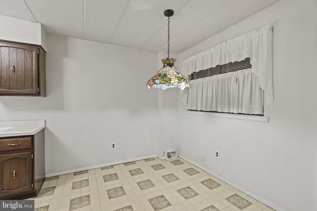 a view of an empty room with a chandelier fan and a window