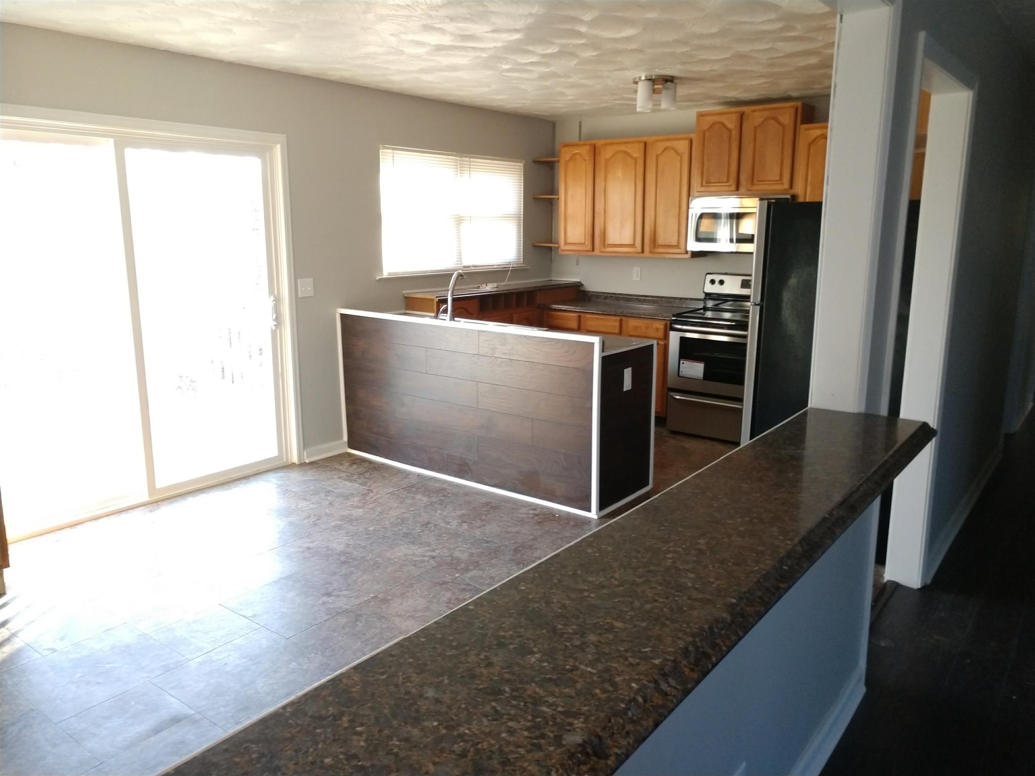 1240 Black Road Cunningham, TN 37052 - Photo 3 of 12 a kitchen with stainless steel appliances granite countertop a stove a sink and a refrigerator
