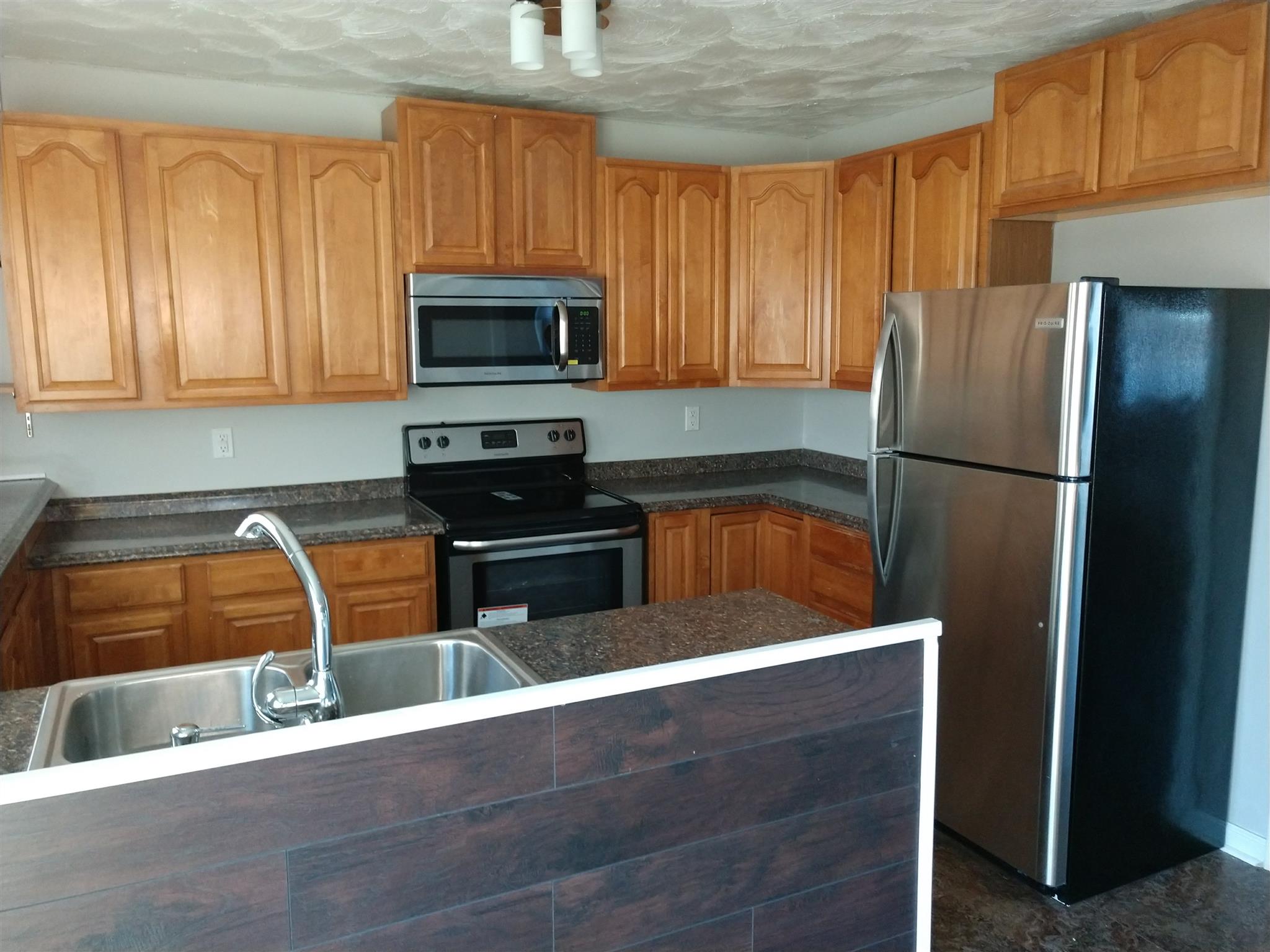 1240 Black Road Cunningham, TN 37052 - Photo 4 of 12 a kitchen with stainless steel appliances granite countertop a refrigerator a stove and a sink with wooden cabinets