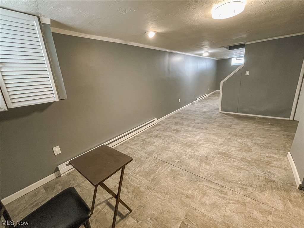 24709 Emery Road Warrensville Heights, OH 44128 - Photo 28 of 34 Basement with baseboard heating, light tile floors, crown molding, and a textured ceiling