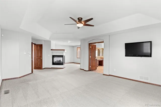 a view of an empty room with window and a kitchen