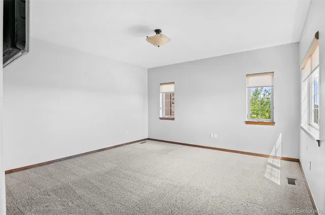 an empty room with windows and ceiling fan