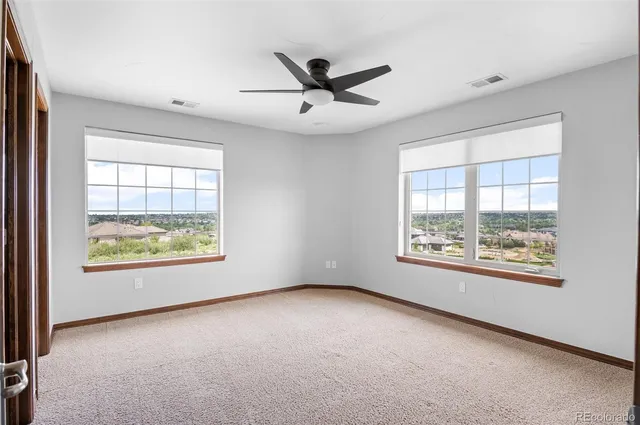 an empty room with windows and chandelier fan