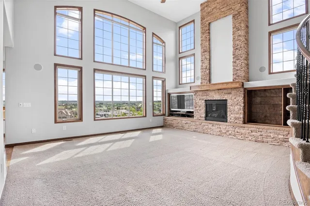 a view of an empty room with a fireplace and windows