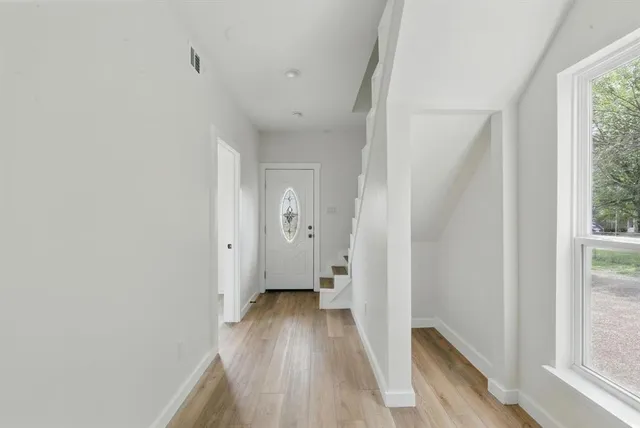 a view of a hallway with wooden floor and a bathroom