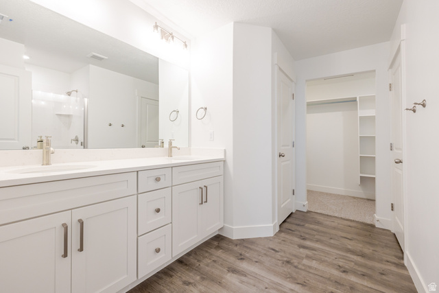 4769 Olive Avenue, Unit 411 Mapleton, UT 84664 - Photo 12 of 19 Full bathroom featuring double vanity, light wood-style flooring, a shower stall, and a walk in closet