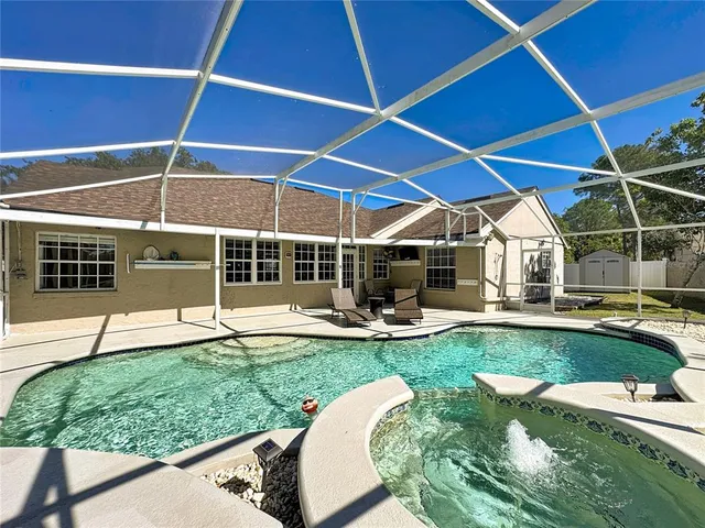 a view of a swimming pool with a patio and a backyard
