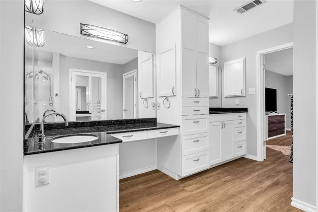 a kitchen with stainless steel appliances granite countertop a sink and cabinets with wooden floors