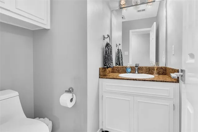 a bathroom with a granite countertop sink a toilet and mirror