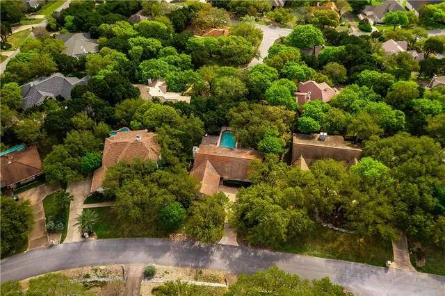 an aerial view of residential houses with outdoor space and trees