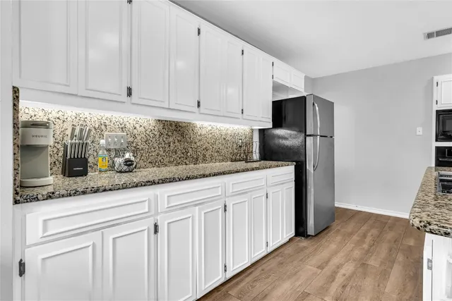 a kitchen with stainless steel appliances granite countertop white cabinets and a refrigerator