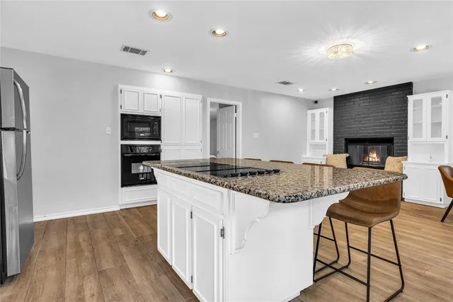 a kitchen with kitchen island granite countertop a stove and a wooden floors