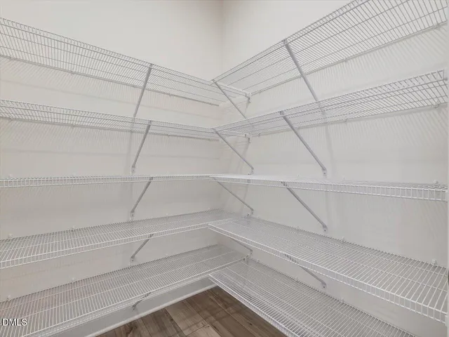 a view of a hallway with wooden floor and a bathroom