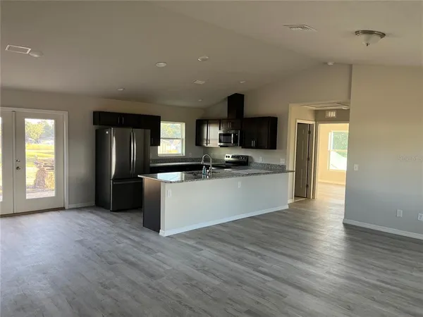 a large kitchen with stainless steel appliances granite countertop a large counter top and a stove with wooden floor