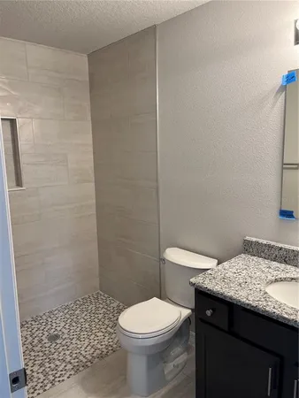 a bathroom with a granite countertop toilet and a sink