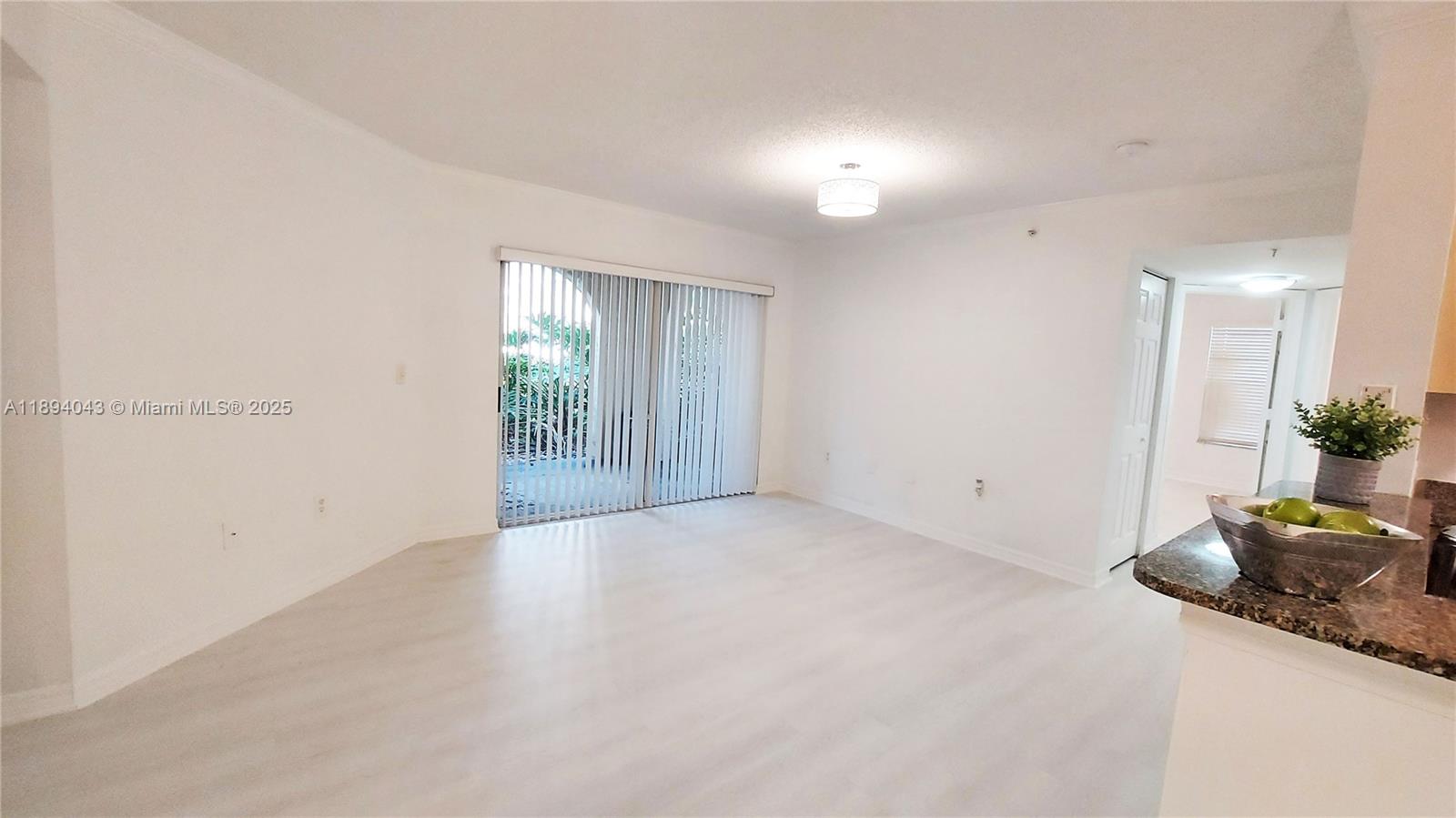 a view of an empty room with wooden floor and a potted plant