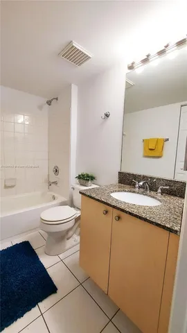 a bathroom with a granite countertop sink a toilet a mirror and bathtub