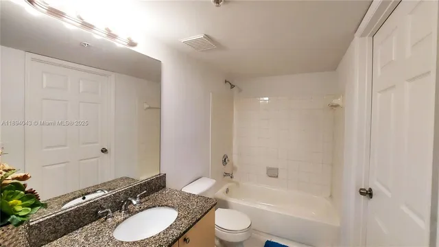 a bathroom with a granite countertop sink toilet a shower and a mirror