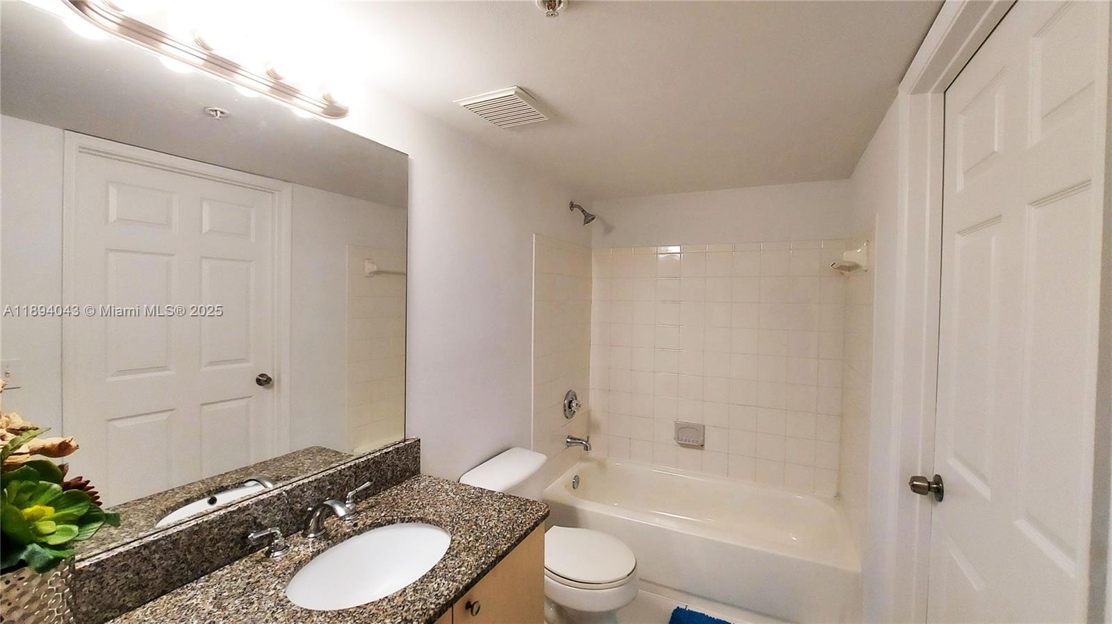 2457 Centergate Drive, Unit 108 Miramar, FL 33025 - Photo 8 of 18 a bathroom with a granite countertop sink toilet a shower and a mirror