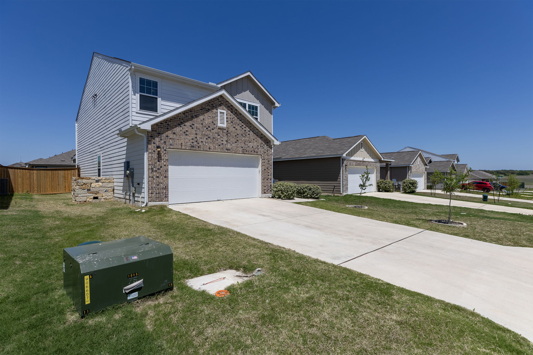409 Line Of Fire Way Jarrell, TX 76537 - Photo 3 of 30 Two-story residence featuring a brick and siding exterior, attached two-car garage, concrete driveway, covered front entry, front-facing windows, and a fenced side yard.