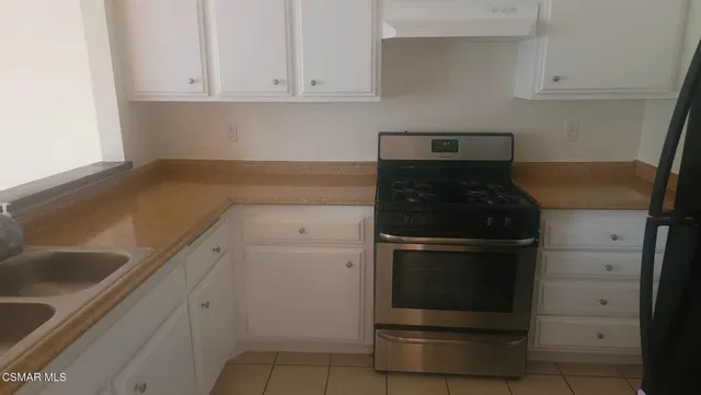 a kitchen with granite countertop white cabinets and stainless steel appliances