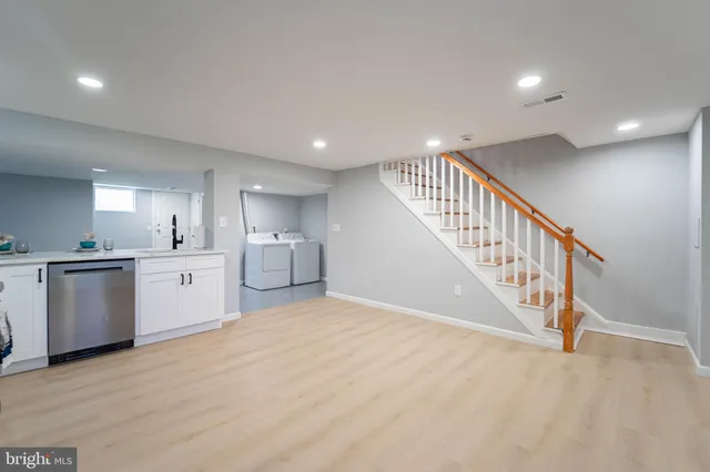 a view of a kitchen with a sink and dishwasher a stove top oven with wooden floor