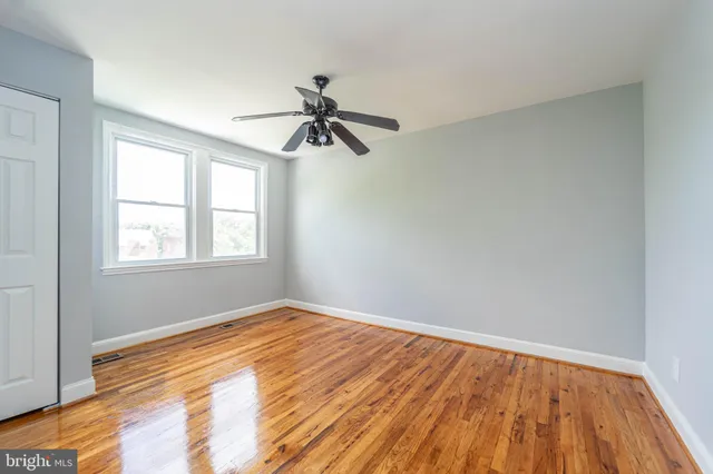 a view of empty room with wooden floor and fan