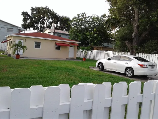 a view of a white house with a yard and table
