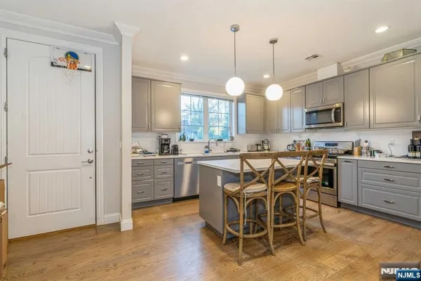a kitchen with kitchen island granite countertop wooden floors and white cabinets