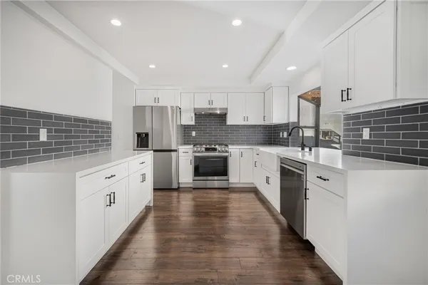 a large kitchen with cabinets a sink and white appliances